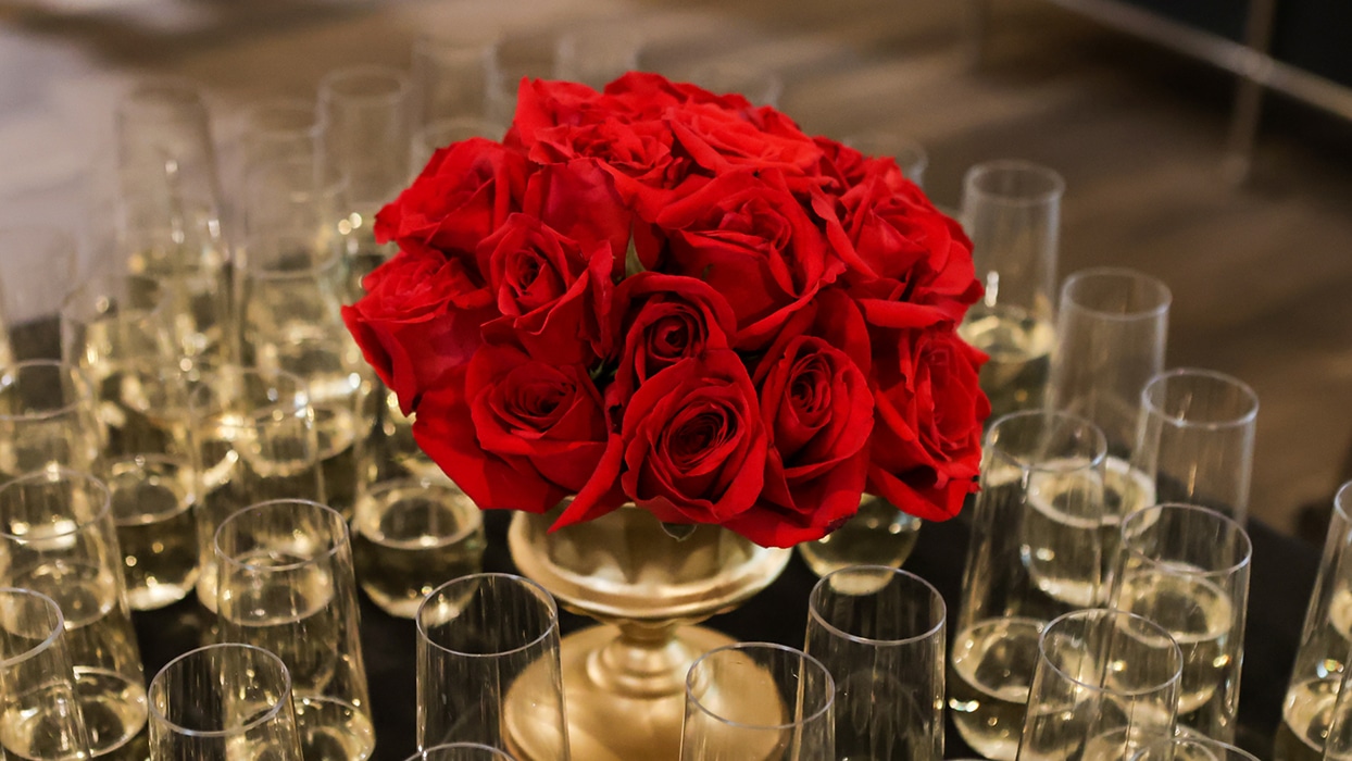 A dozen red roses in a gold centerpiece surrounded by champaign flutes